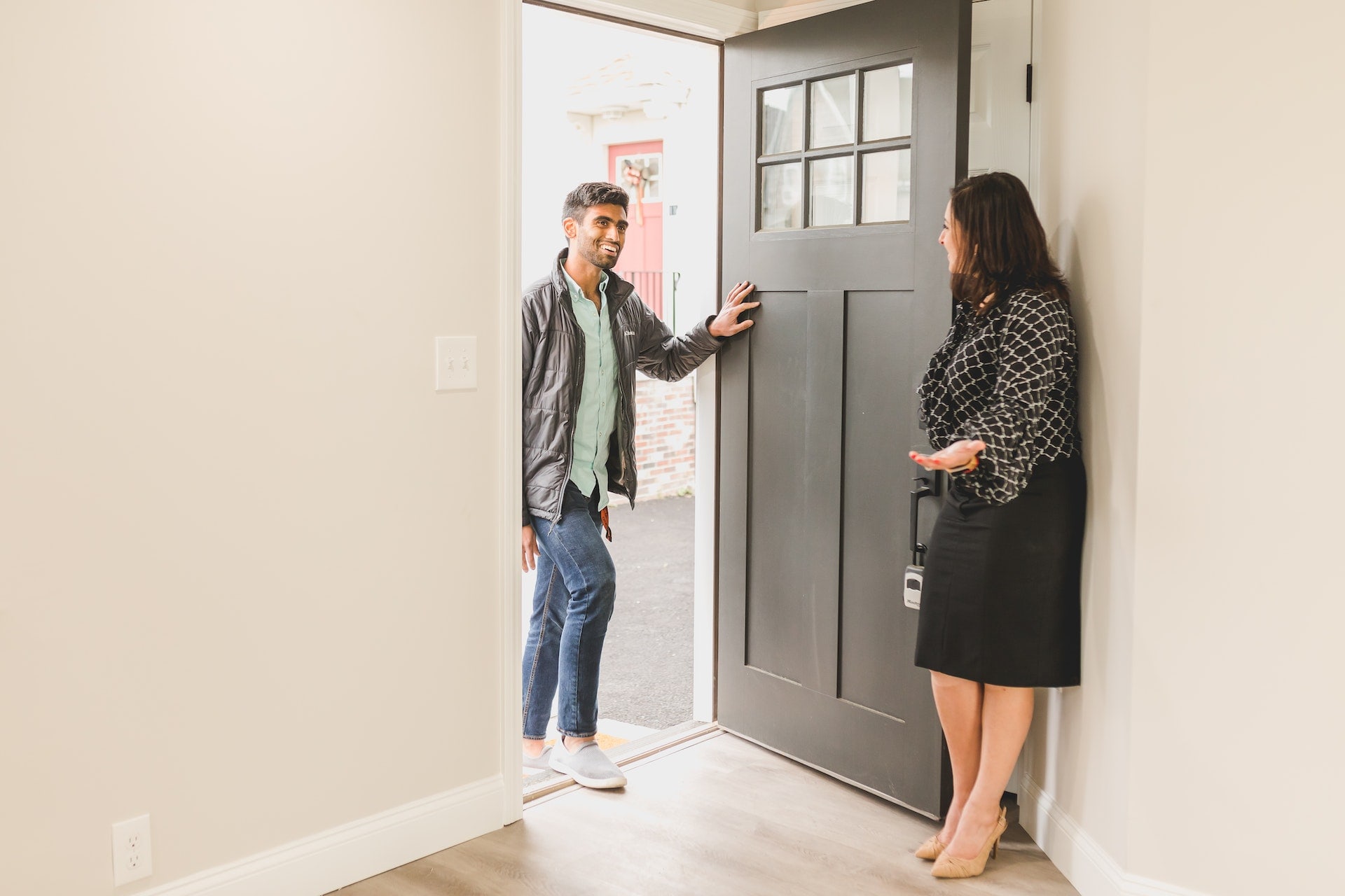 A real estate agent welcoming a buyer at the front door of a home