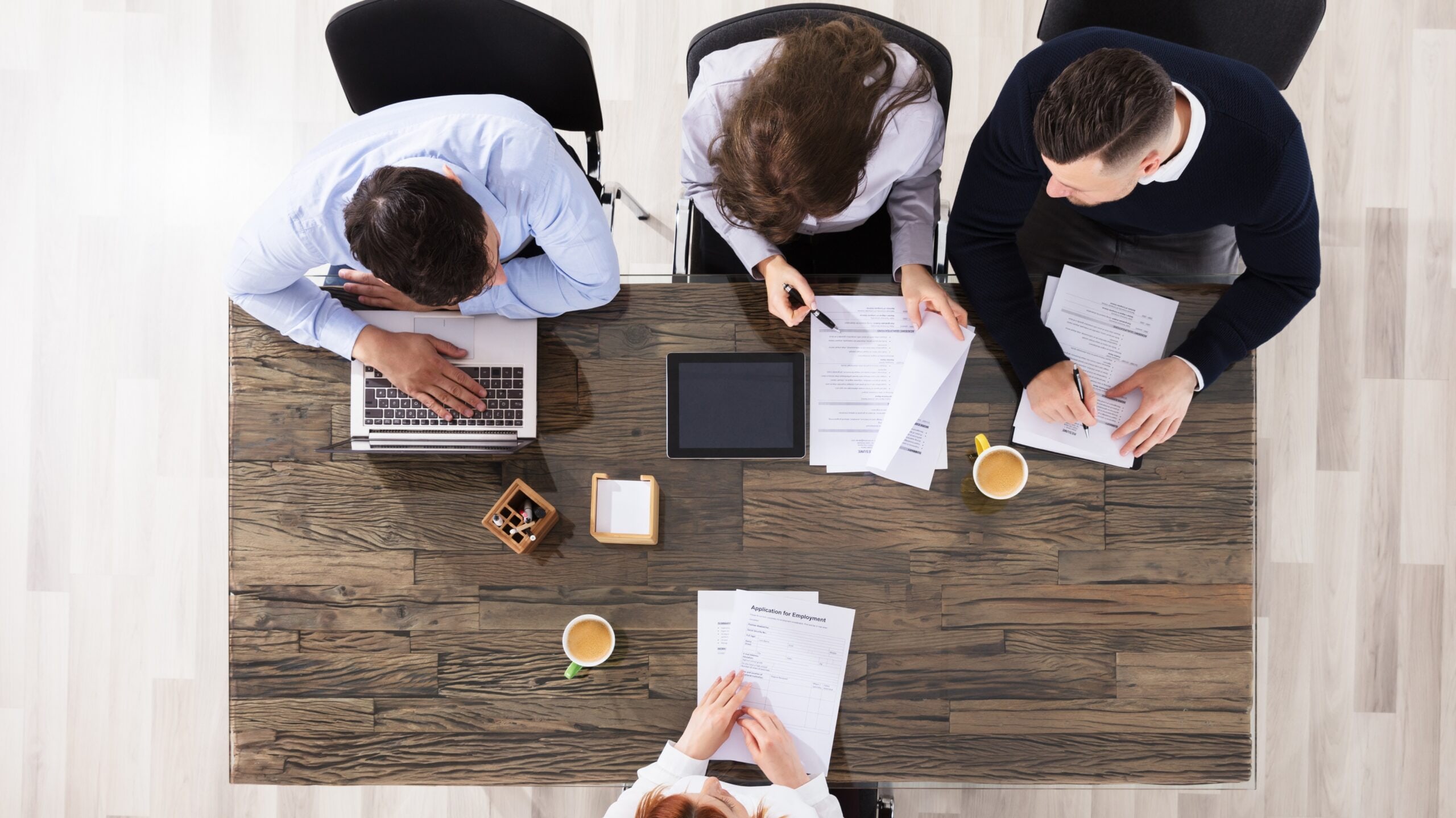 People reviewing paperwork together around a table, seen from above