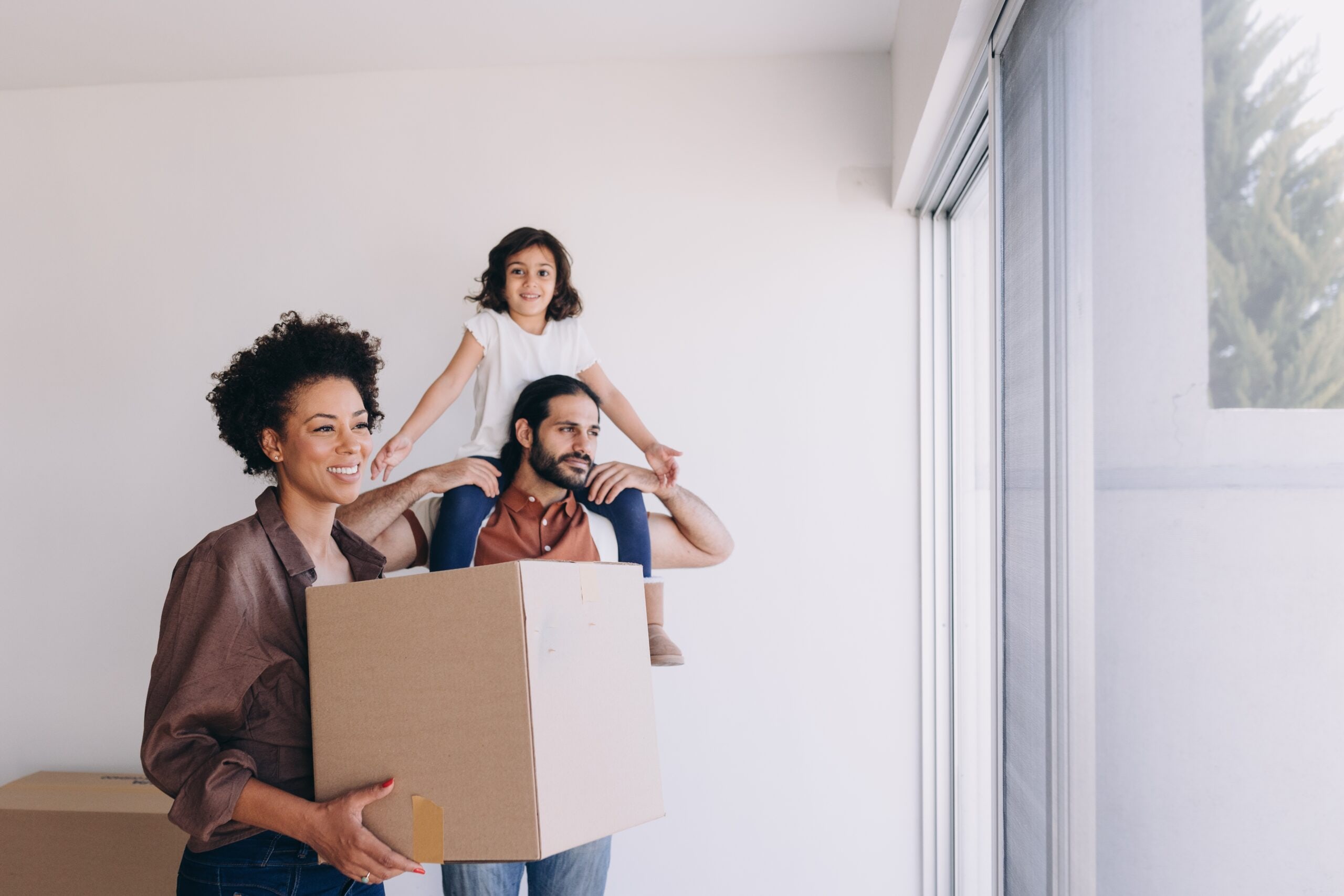 A family carrying moving boxes into their new home