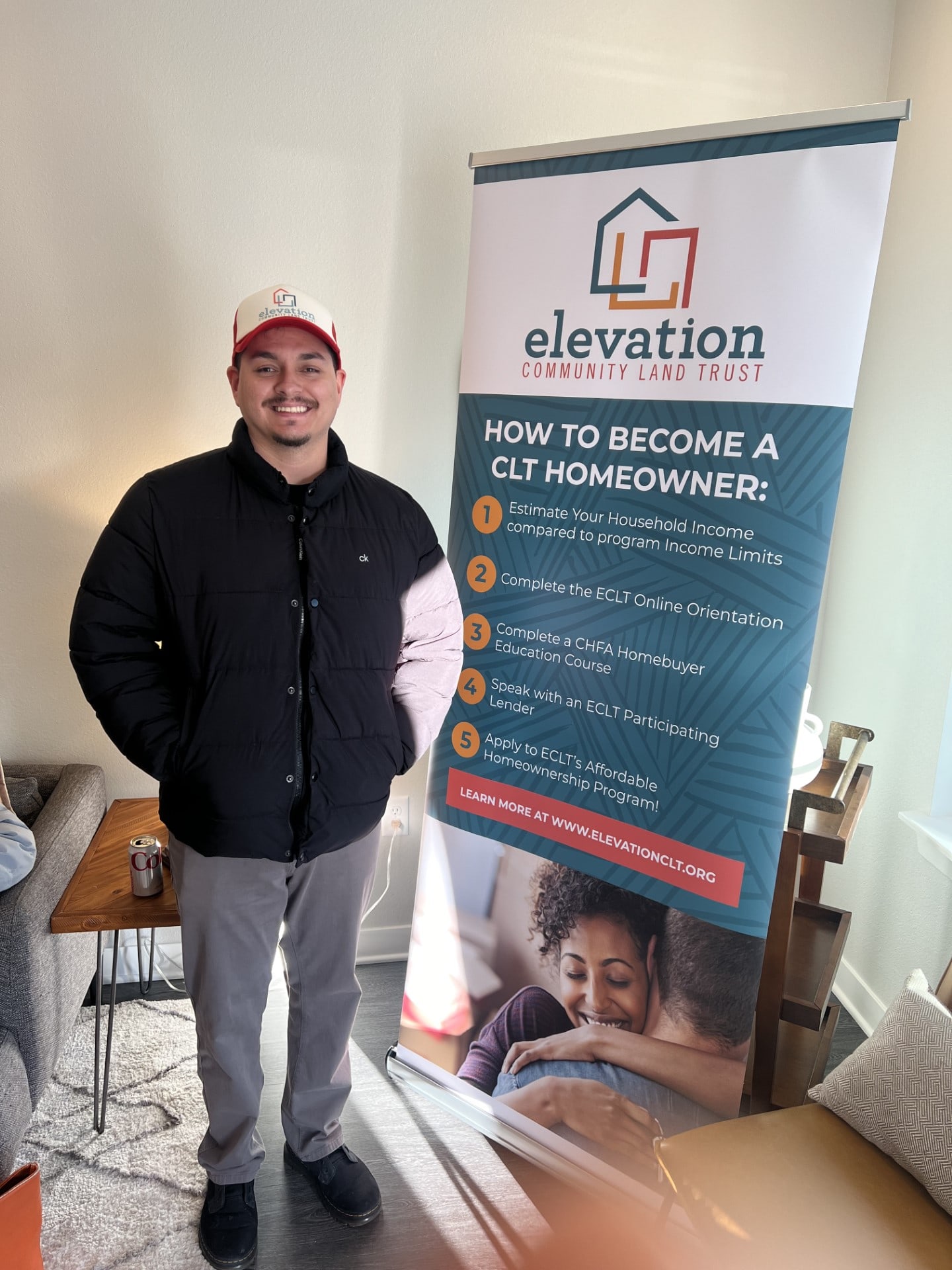 An ECLT staff member next to a banner explaining how to become a CLT homeowner