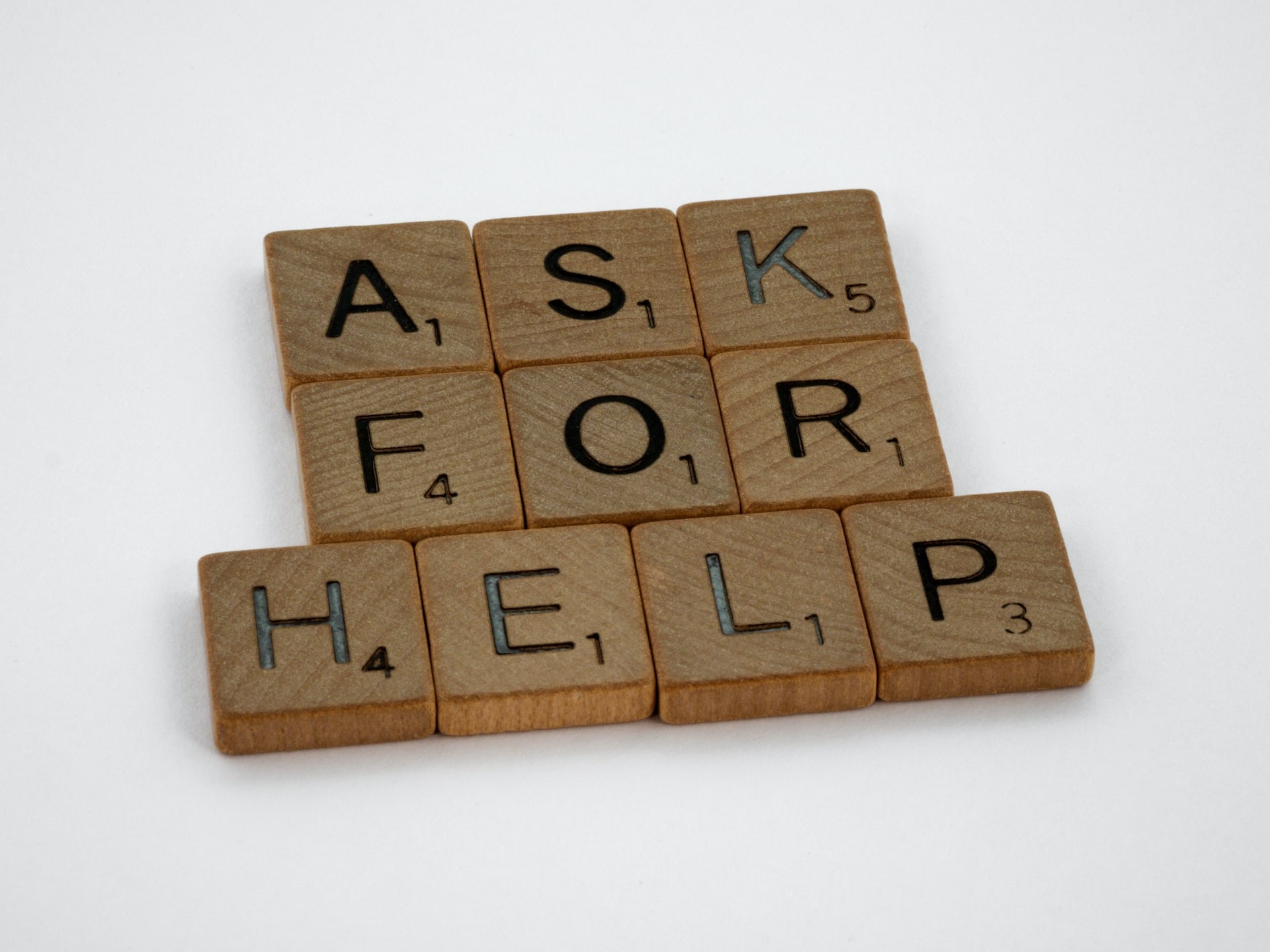 Wooden letter tiles spelling “for help”