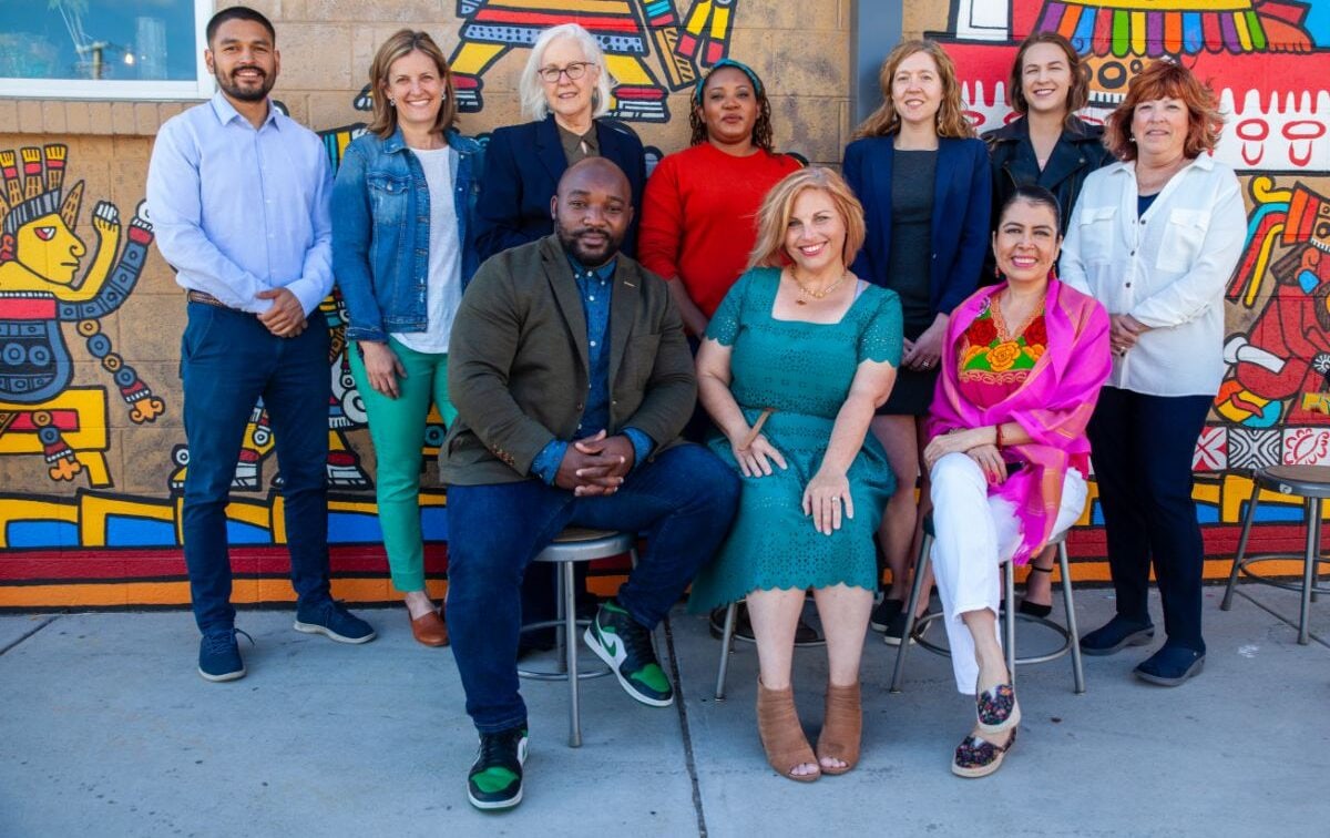 The Elevation Community Land Trust team together in front of a colorful mural